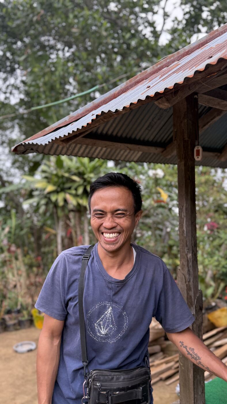 Dwi, souriant, devant la maison familiale